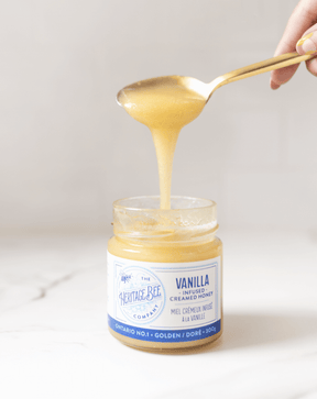 Heritage Bee Co's premium smooth vanilla infused wildflower honey pictured running off a spoon. Perfect to eat by the spoonful.